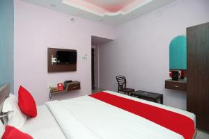 普里Goroomgo Savashi Puri的一间卧室设有红色和白色的床和一台电视。