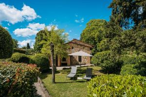 索维奇勒Borgo Il Poggiaccio Residenza d'Epoca的一座房子,配有两把椅子和一把伞