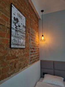 罗兹Kamienica Łódzka的一间设有砖墙、一张床和一盏灯的房间