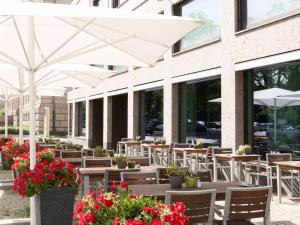 柏林柏林提尔公园诺富特酒店的一间带桌椅和白色遮阳伞的餐厅