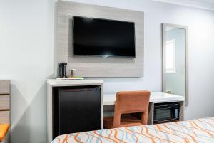 Bell加州贝尔洛杉矶旅行宾馆及套房酒店的酒店的客房,配有书桌和墙上的电视