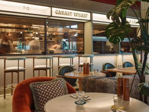 伦敦TRIBE London Canary Wharf的一间带桌椅和柜台的餐厅