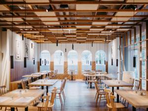 格拉茨ibis Styles Graz Messe的餐厅设有木桌、椅子和窗户。