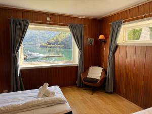 弗洛姆Svingen Guesthouse - Panoramic Fjord Views in Flåm的一间卧室设有大窗户,水中设有一条船
