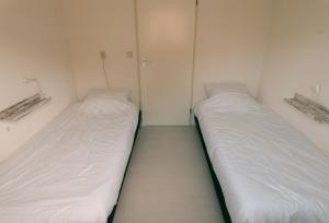 瓦门赫伊曾Rekerlanden 275的配有白色墙壁的小客房内的两张床