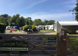 彭赞斯Stream Valley Holiday Park的一个带标志的大门,上面有阅读强山谷度假和大篷车公园的标志