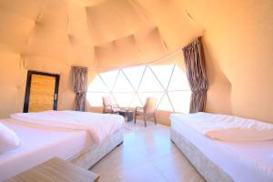瓦迪拉姆Adel rum camp bubbles的一间卧室设有两张床、一张桌子和一个窗口