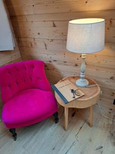 拉蓬Hotel Chesa Staila的粉红色的椅子和带灯的桌子