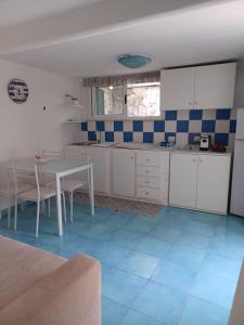 伊斯基亚simona 2的厨房配有桌子,铺有蓝色瓷砖地板。