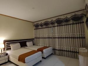 哥伦打洛省H.V HOTEL BANDARA的酒店客房设有两张床和窗户。