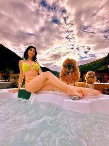 瓦尔迪登特罗Nira Mountain Resort Futura的坐在游泳池边的女人,有两条狗