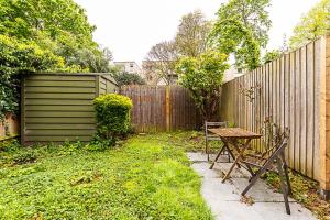 伦敦Cosy and Modern Battersea Home的花园设有木栅栏和木桌