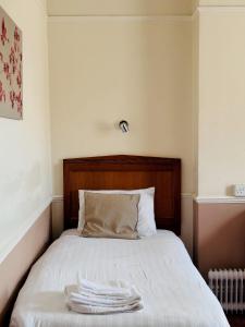 拉格比拉格比格罗夫纳酒店的一张铺有白色床单的床和木制床头板