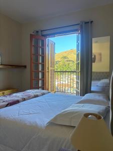 坎波斯杜若尔当Pousada Aconchego na Montanha的一间卧室设有三张床和大窗户