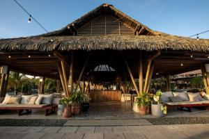 普拉纳维瑙Villa #32 - Blue Venao, Playa Venao的大型草屋顶凉亭,配有沙发和植物