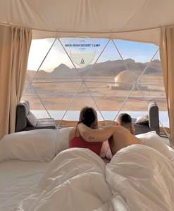 瓦迪拉姆Wadi Rum desert camp的躺在床上的男人和女人看着窗外
