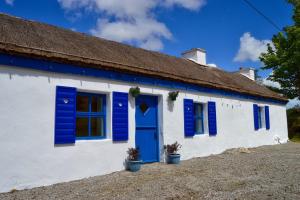 DoocharyBeautiful Thatched Adderwal Cottage Donegal的白色的房子,有蓝色百叶窗和屋顶