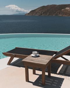 凯勒里瓦迪米科诺斯潘泰恩公寓酒店的坐在泳池旁的木桌旁的咖啡杯