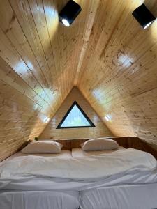 哈塔伊Karaağaç Bungalov & Tiny House的木制客房的一张床位,设有窗户