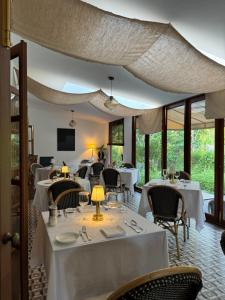 清迈Sela Chiangmai的餐厅设有白色的桌椅和窗户。