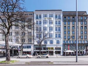 汉堡Hotel Kronprinz Hamburg Hauptbahnhof的一座白色的大建筑,前面有汽车停放