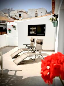 马贝拉Marbella Village的庭院配有两把椅子,白色墙壁上配有电视