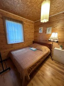 Višķi玛兹里格兹迪纳度假屋的木制客房内的一间卧室,配有一张床