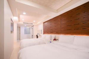 中坜伯爵商务旅店的配有白色床单的酒店客房内的两张床