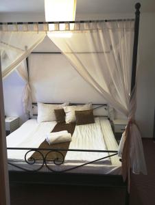 奥拉迪亚RHC皇家酒店的卧室配有带白色床单和枕头的天蓬床。