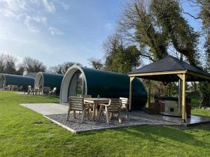 唐帕特里克Kinelarty Luxury Glamping Pods Downpatrick的桌子和椅子以及田野上的帐篷