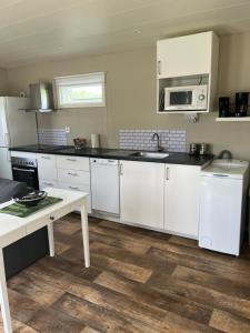 HebergTiny house max 4 people的厨房配有白色橱柜、水槽和桌子