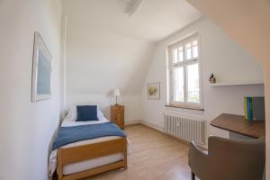 巴塞尔Charmante Altbauwohnung am Rhein的一间卧室配有一张床、一张书桌和一个窗户。