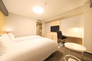 成田成田Richmond酒店的一间酒店客房,配有一张白色的床和一张书桌