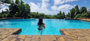 圣玛丽La Villa Ankarena Location de villa entière avec piscine privée à débordement sur parc aménagé Wifi TV Plage à 5 minutes à pied的站在游泳池的水中的女人