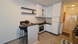 巴什卡沃达Apartments Mediteraneo的厨房配有白色橱柜和带凳子的台面