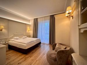 梅拉诺Windsor Merano Hotel & Suites的配有一张床和一把椅子的酒店客房