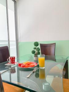卡塔赫纳Hotel Cabreromar By GEH Suites的玻璃桌,上面放着一盘食物和一杯橙汁