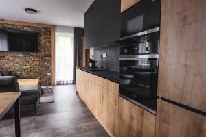 比拉Luxusní Apartmán Domovjanka - SKALKA FAMILY的一间厨房,配有黑色家电和砖墙