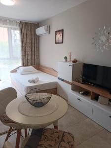 内塞伯尔Megi Apartments, Nesebar sity的一间卧室配有一张床、一张桌子和一台电视。