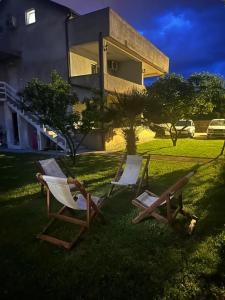 赫尔采格诺维Apartmani Zelenika的两把椅子坐在房子前面的草上