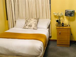 姆巴巴内GoldenWays Motel的一间卧室配有一张床和一张带台灯的桌子