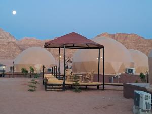 瓦迪拉姆Taj Wadi Rum camp的沙漠中带桌椅的凉亭