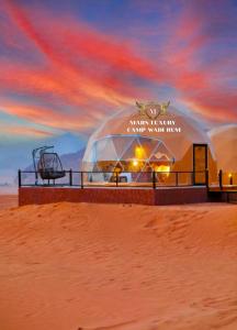 瓦迪拉姆MARS LUXURY CAMP WADi RUM的海滩上的圆顶建筑,享有日落美景
