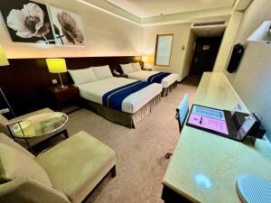 花莲市HiYesHotel勤天商旅-花蓮館的酒店客房配有两张床和一张带笔记本电脑的书桌