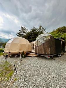 富士河口湖Fuji Dome Glamping的几顶帐篷和砾石上的拖车