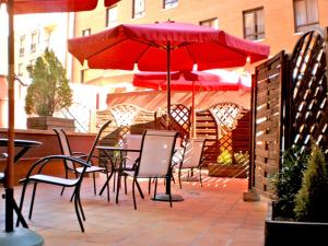 洛格罗尼奥穆列塔酒店的露台的红色遮阳伞下的桌椅