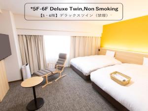 富山富山希泰茨酒店的酒店客房,配有两张床和椅子