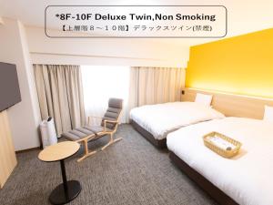 富山富山希泰茨酒店的酒店客房,配有两张床和椅子