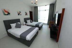 麦纳麦Noor Amwaj Hotel & Apartment的酒店客房设有两张床和一台平面电视。