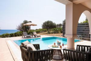 罗德岛卡利地亚KRESTEN ROYAL Euphoria Resort的毗邻大海的带椅子和桌子的游泳池